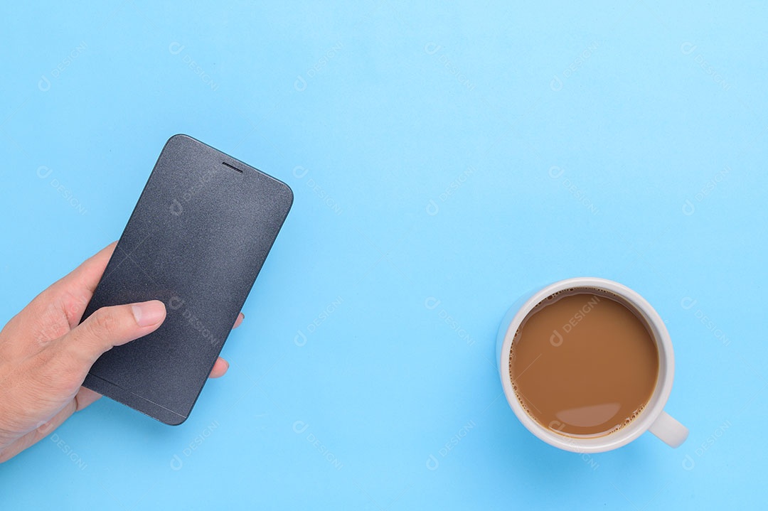 Mão segurando o smartphone e a xícara de café no fundo azul