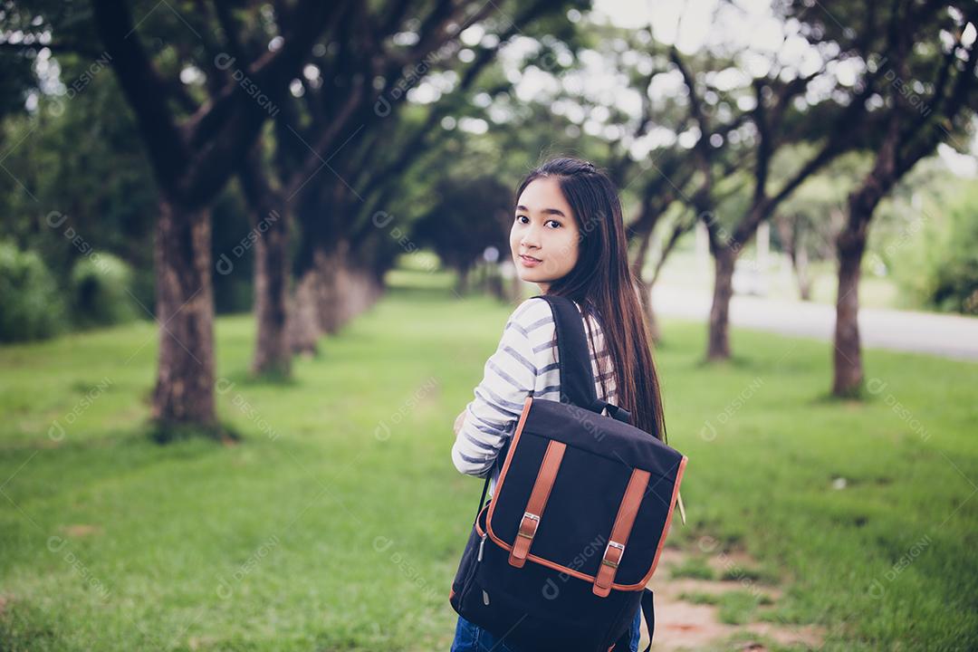 bela estudante asiática segurando livros e sorrindo para a câmera e conceito de aprendizagem e educação no parque