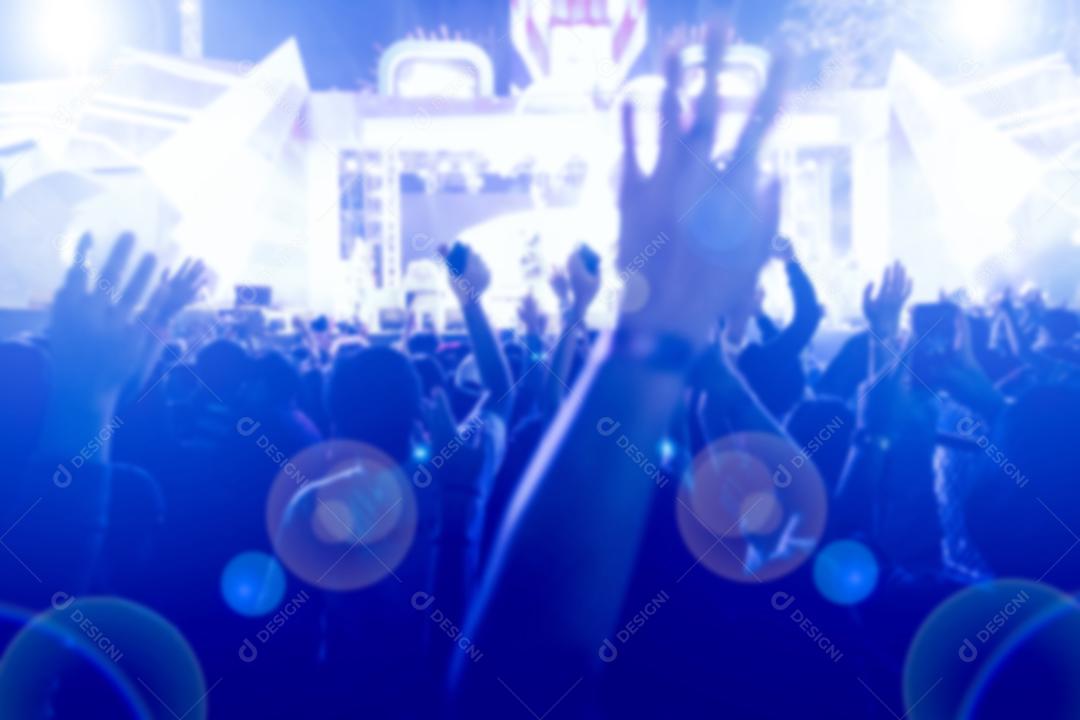 silhuetas da multidão do concerto na vista traseira da multidão do festival levantando as mãos nas luzes brilhantes do palco