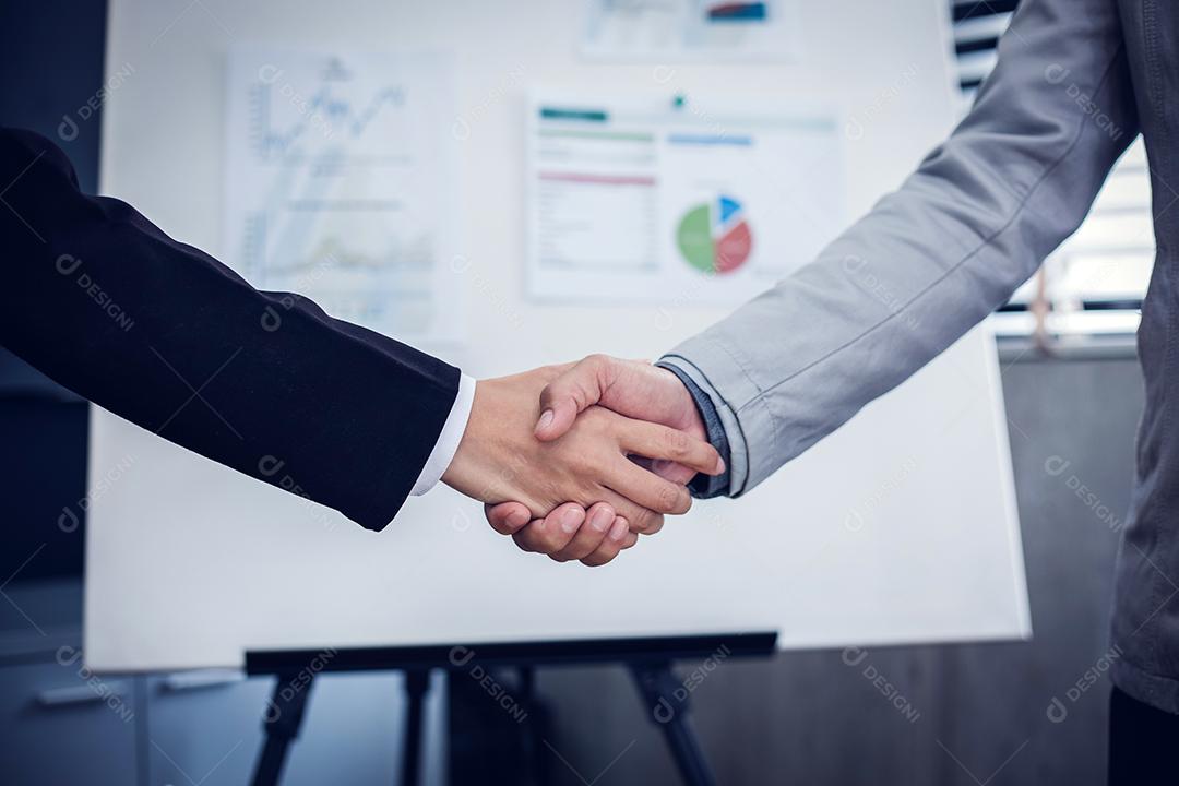 Empresários asiáticos apertando as mãos e sorrindo seu acordo para assinar contrato e terminar uma reunião