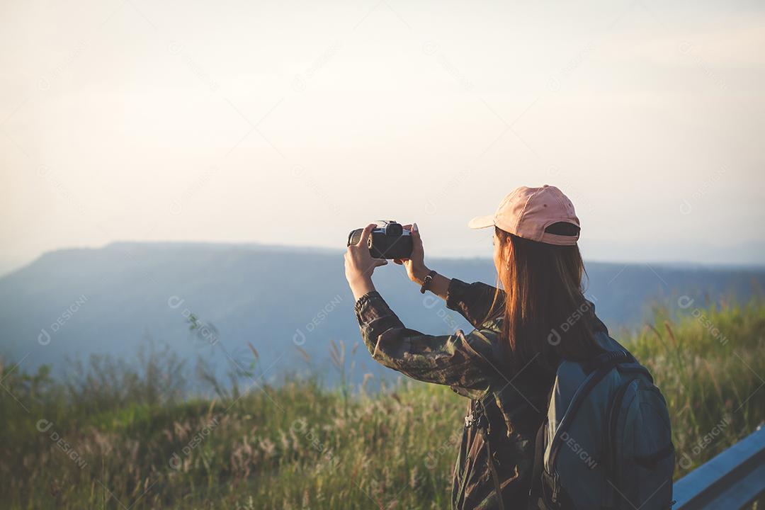 Mulher jovem asiática caminhando com mochilas de amigos caminhando juntos e olhando o mapa e tirando a câmera