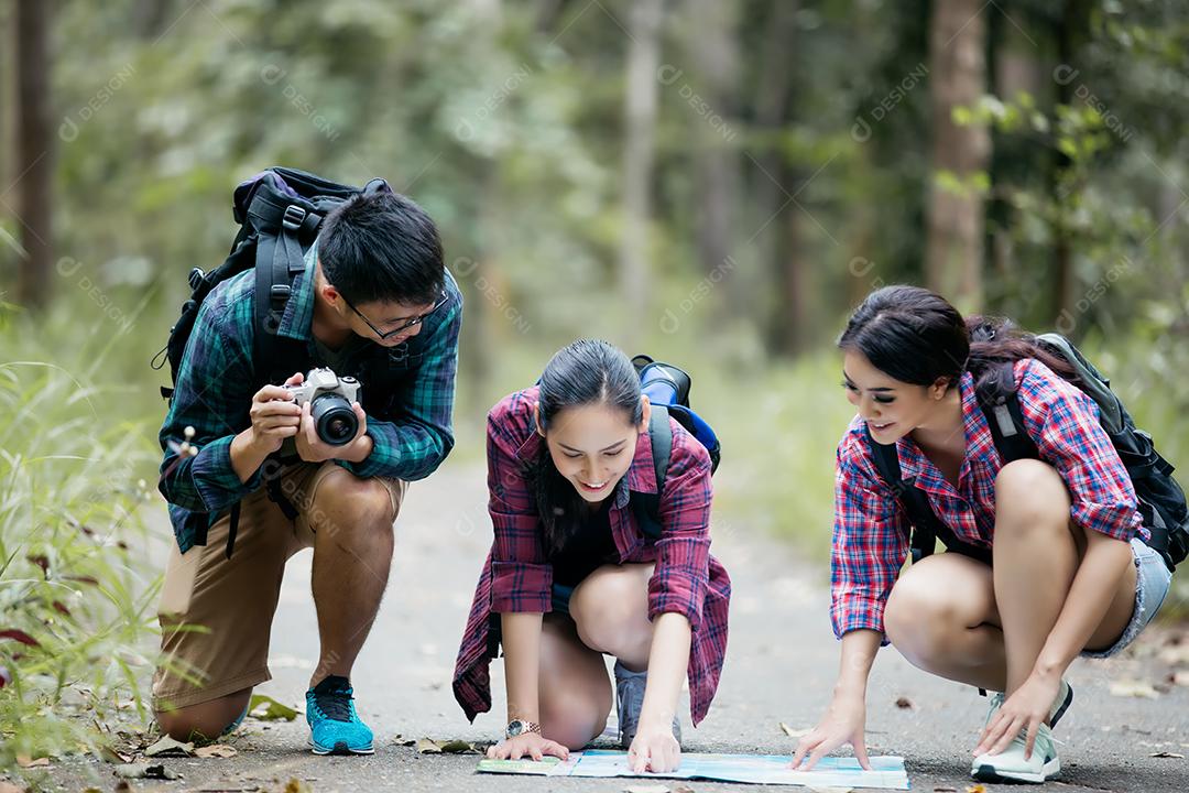 Grupo asiático de jovens Caminhando com mochilas de amigos caminhando juntos e olhando o mapa e tirando a câmera fotográfica