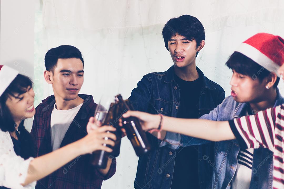 Grupo asiático de amigos festejando com bebidas alcoólicas de cerveja e jovens se divertindo em um bar brindando coquetéis.