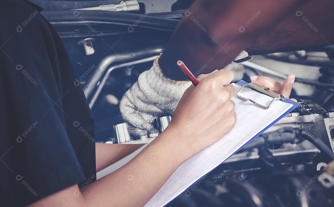 Engenheiras e técnicas asiáticas estão verificando o mecânico e inspecionando um carro na oficina de automóveis a lista no quadro