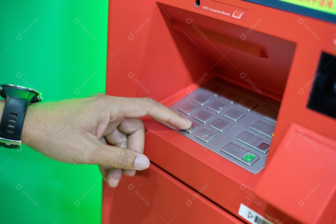 Mão de homem digitando o código PIN/senha no teclado da máquina ATM/banco