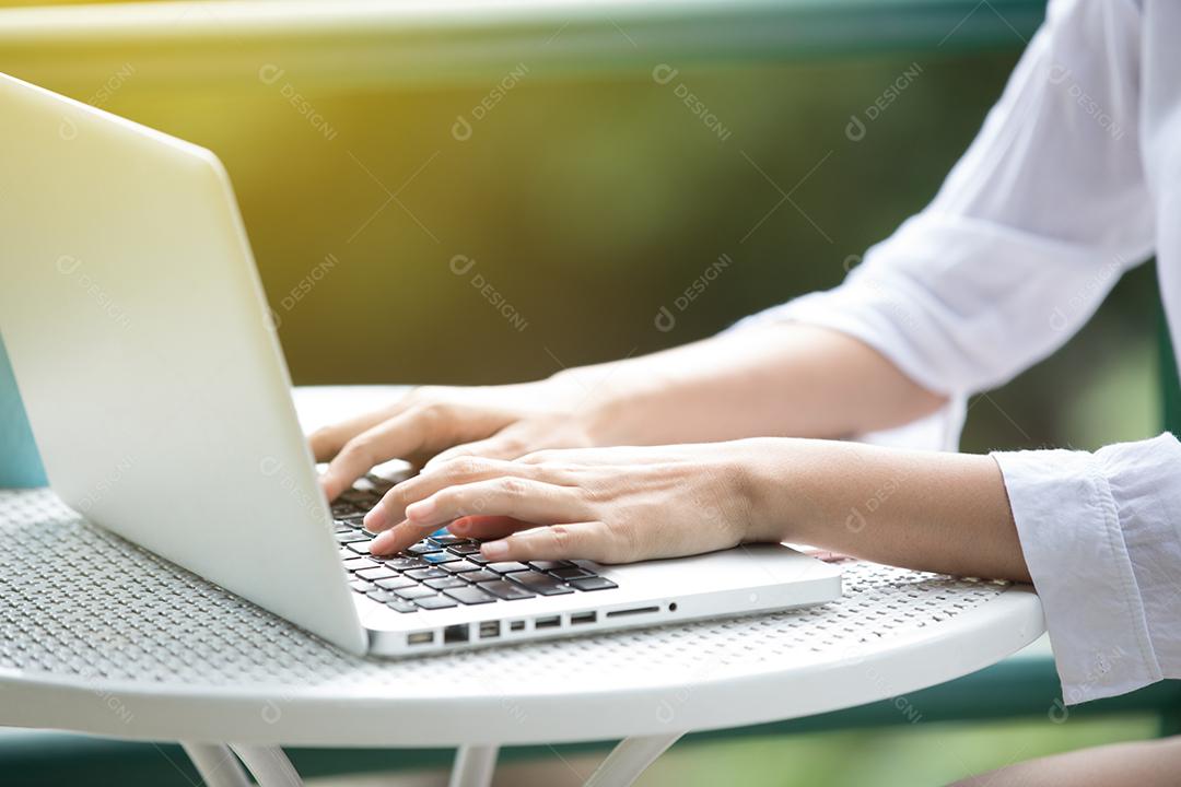 Mulher de negócios asiáticos usando notebook e sorrindo felizes por trabalhar