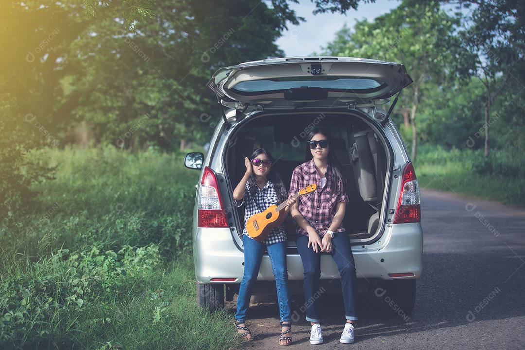 Menina feliz com família asiática sentada no carro para curtir a viagem e as férias de verão na van campista