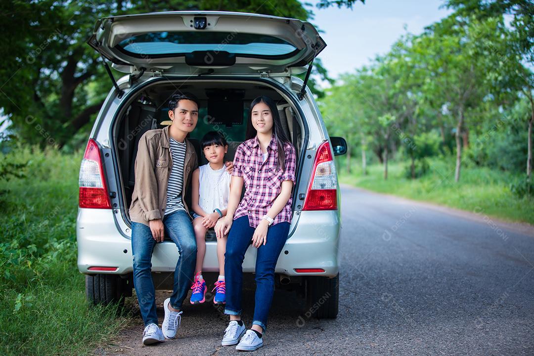 Menina feliz com família asiática sentada no carro para curtir a viagem e as férias de verão na van campista