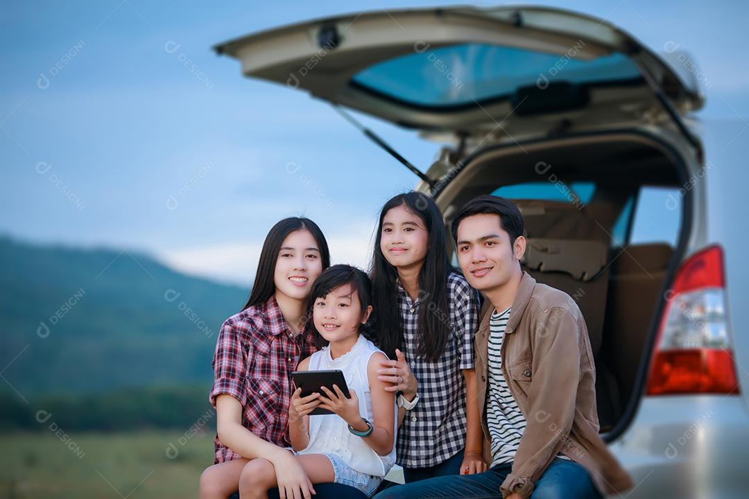 Menina feliz com família asiática sentada no carro para curtir a viagem e as férias de verão na van campista