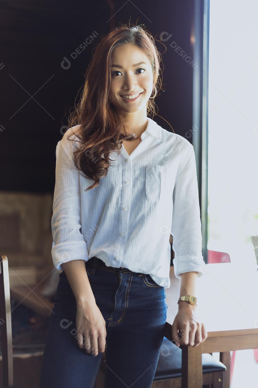 Mulher asiática sorrindo e felizes Relaxando em uma cafeteria depois de trabalhar em um escritório de sucesso.