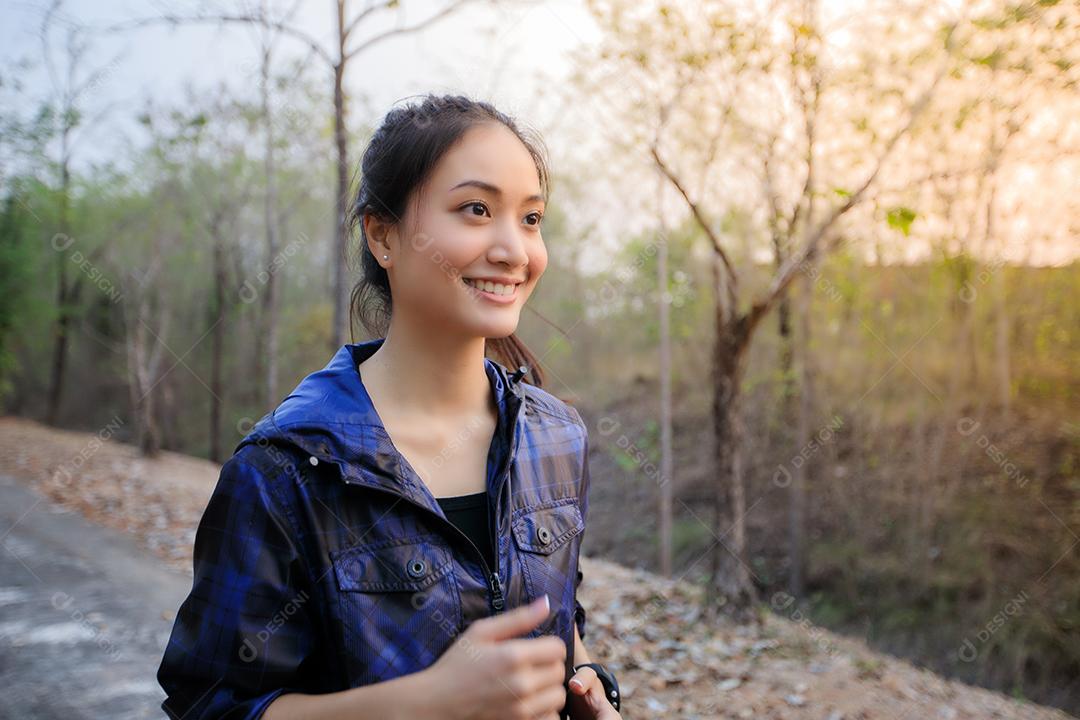 Mulher asiática sorrindo e feliz enquanto correm lá fora na rua no parque.