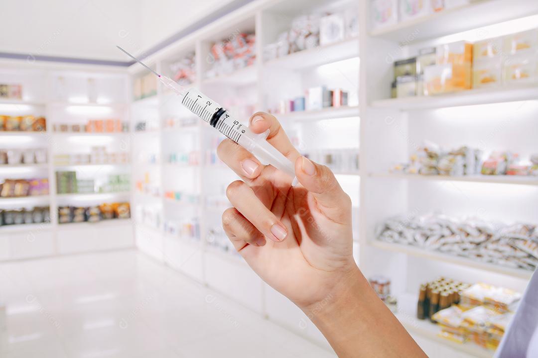 Entrega os médicos enchendo uma seringa na loja de remédios e farmácia para segundo plano