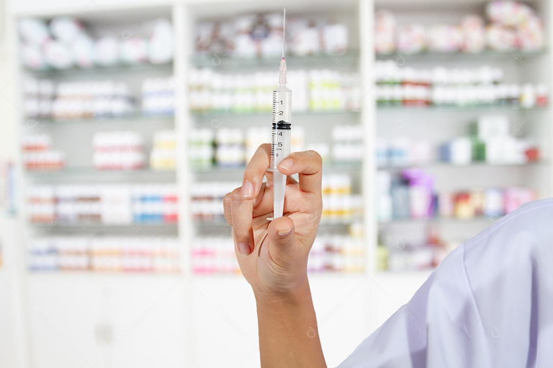 Entrega os médicos enchendo uma seringa na loja de remédios e farmácia para segundo plano