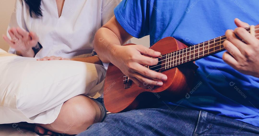 Casal tocando Ukulele e guitarra na cama