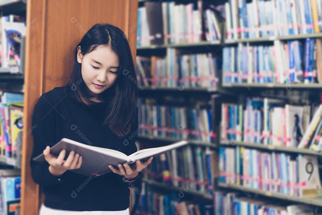 Estudantes asiáticos lendo livros na biblioteca.