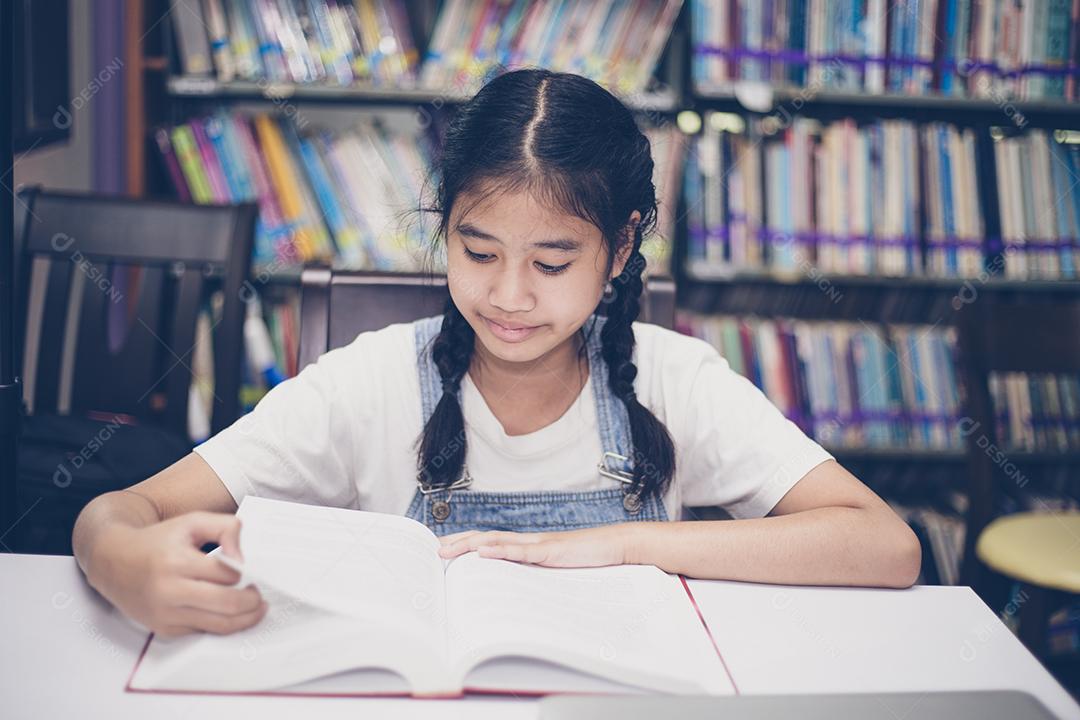 Estudantes asiáticos lendo livros na biblioteca.