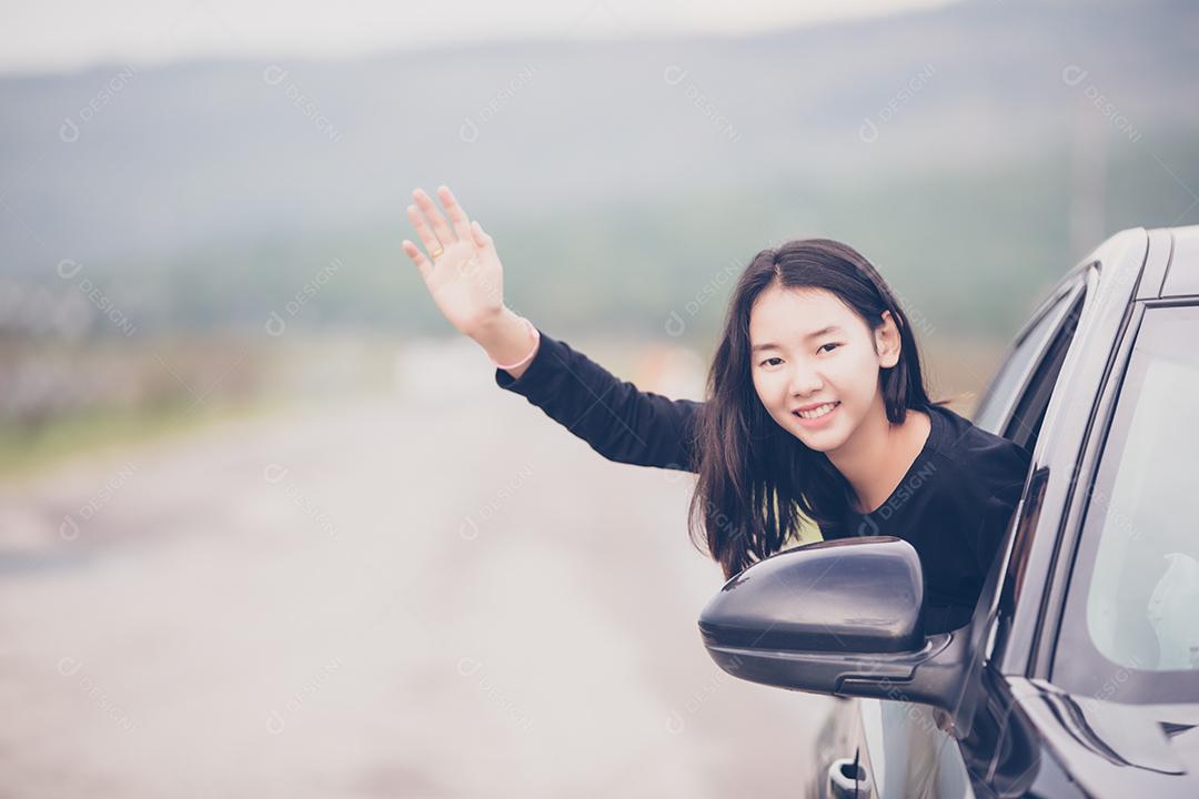 Linda mulher asiática sorrindo e se divertindo dirigindo um carro na estrada para viajar