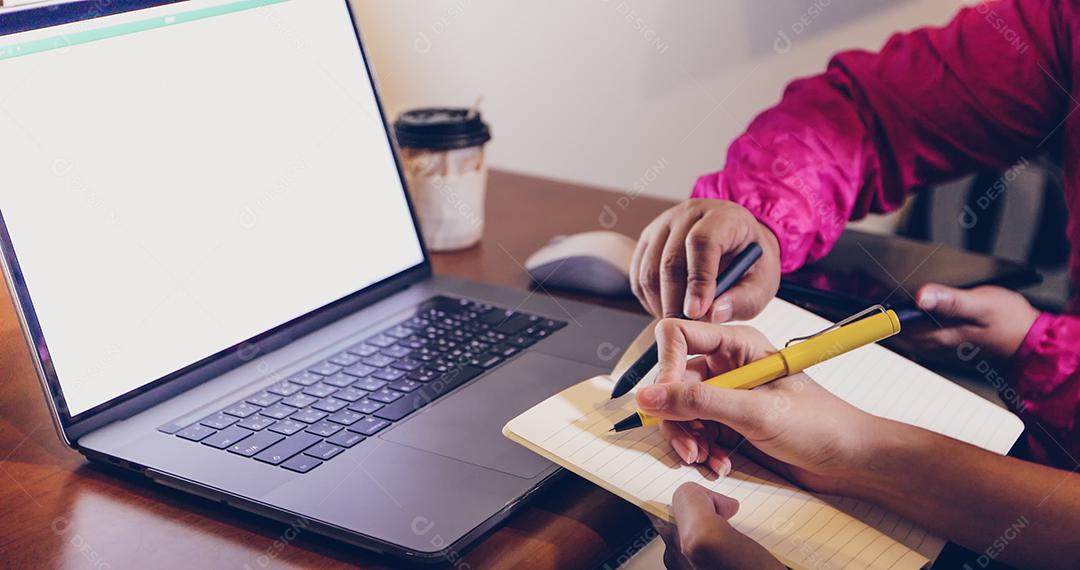 Empresária asiática segurando uma caneta e documentos de análise na mesa de escritório com computador portátil