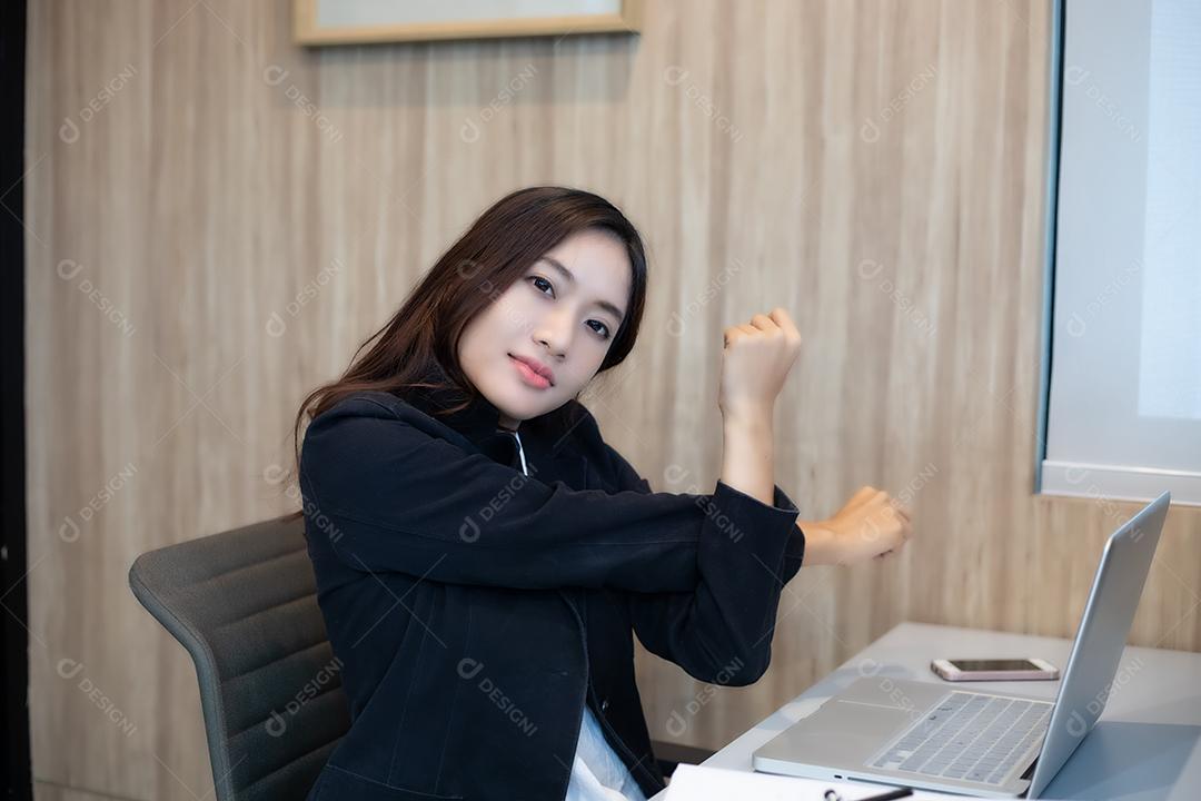 Empresária asiática se estendendo depois de trabalhar duro no escritório
