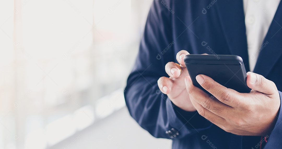 Empresário asiático usando telefone para celulares e mensagens de texto em sua multidão