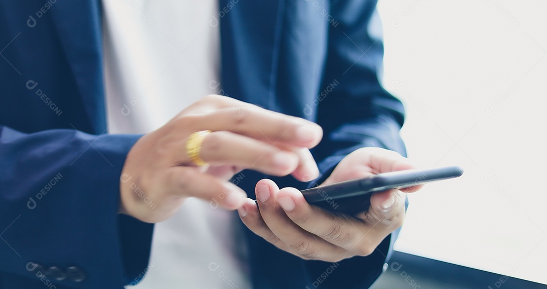 Empresário asiático usando telefone para celulares e mensagens de texto em sua multidão