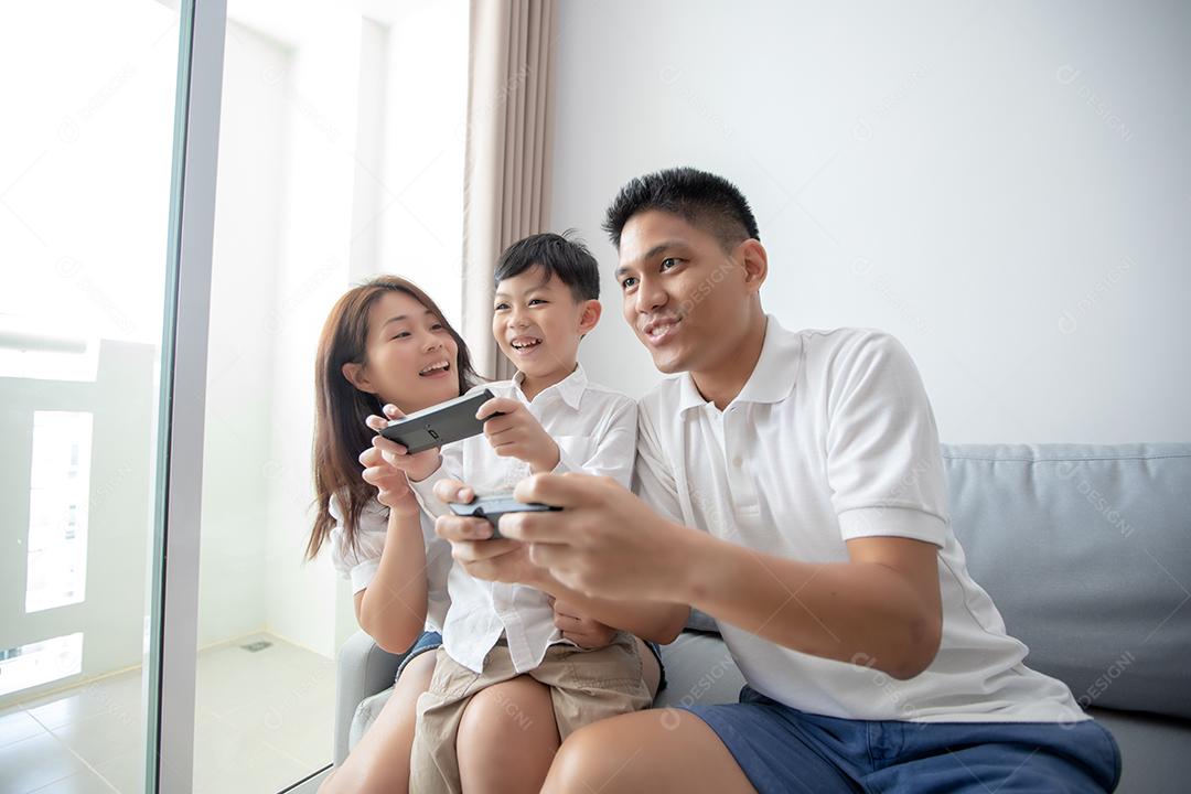 Família asiática se divertindo jogando jogos de console de computador juntos, pai e filho têm os controladores do aparelho