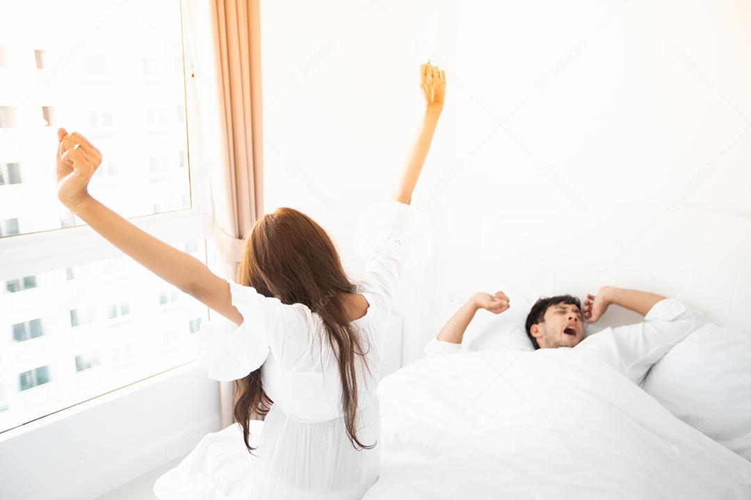 amante de casais acordando em sua cama totalmente descansada e abrindo as cortinas de manhã para tomar ar fresco.