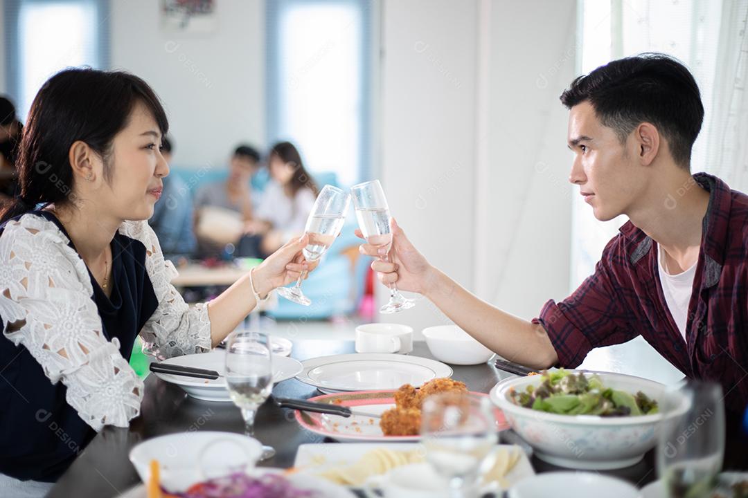 Casal jovem asiático desfrutando de um jantar romântico bebidas à noite enquanto está sentado à mesa de jantar na cozinha juntos