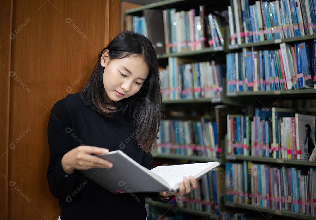Estudantes asiáticos lendo livros na biblioteca.