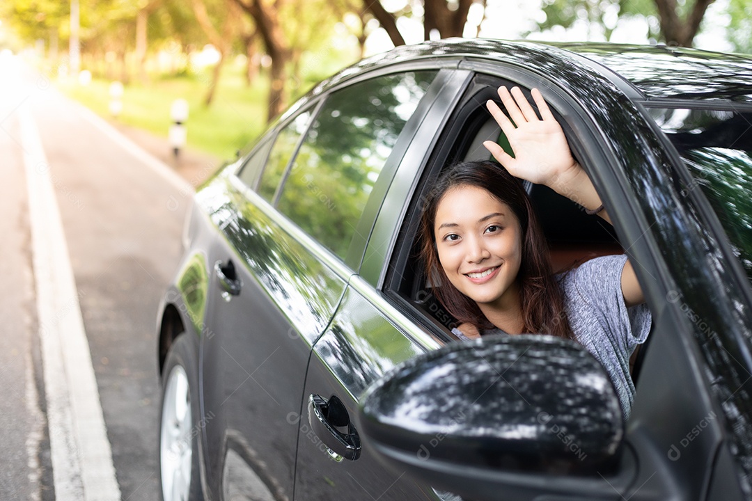 Linda mulher asiática sorrindo e se divertindo dirigindo um carro na estrada