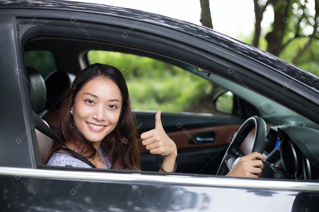 Linda mulher asiática sorrindo e se divertindo dirigindo um carro na estrada