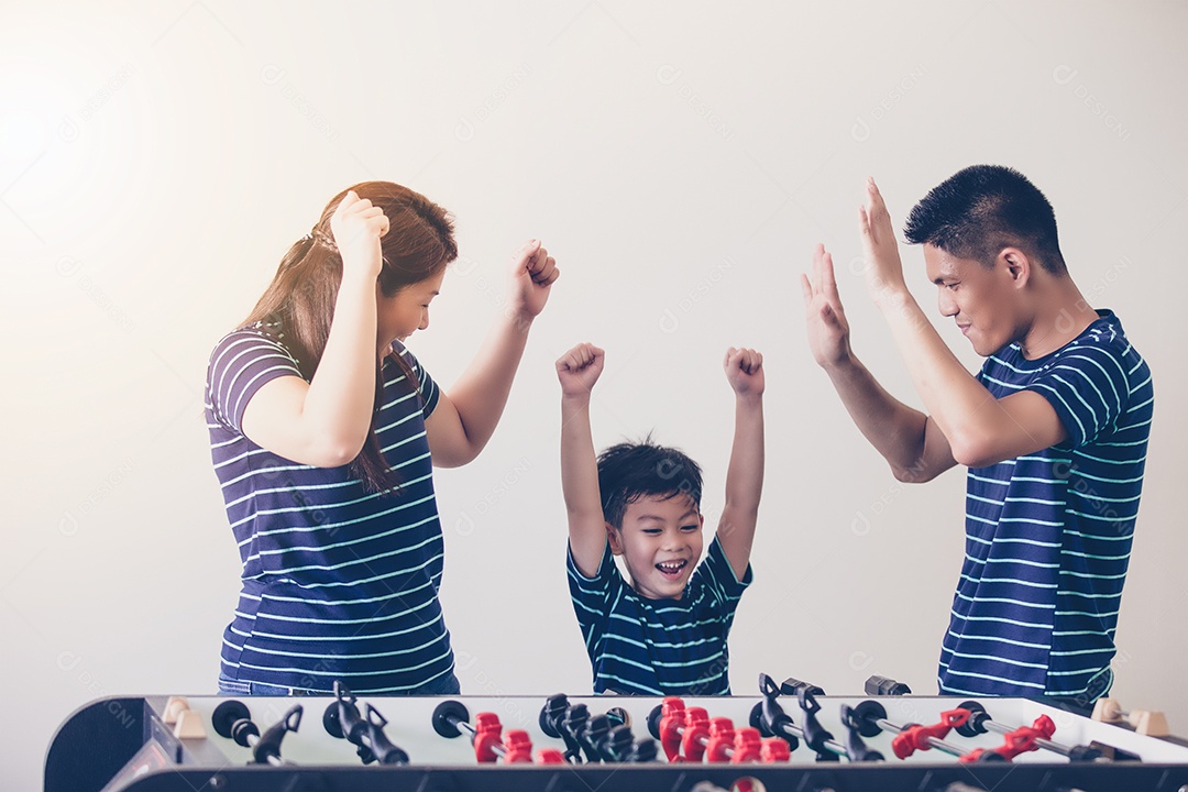 Família feliz jogando futebol de mesa para relaxar nas férias em casa