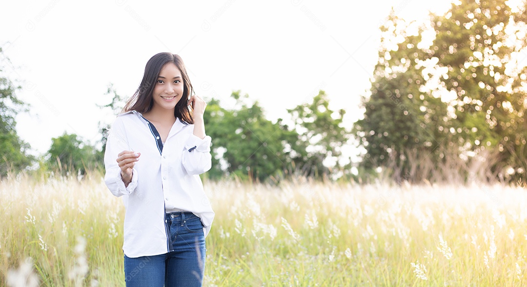 As mulheres asiáticas sorriem felizes no tempo de relaxamento no prado e na grama