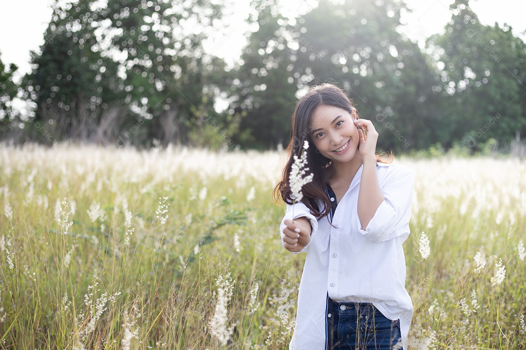 As mulheres asiáticas sorriem felizes no tempo de relaxamento no prado e na grama
