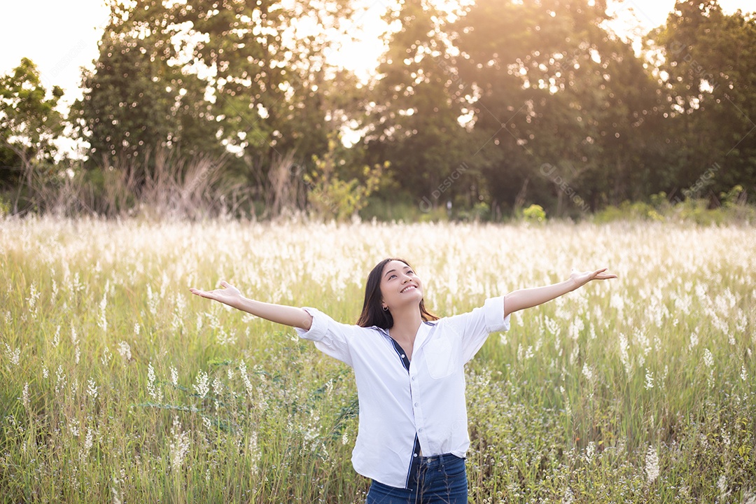 As mulheres asiáticas sorriem felizes no tempo de relaxamento no prado e na grama