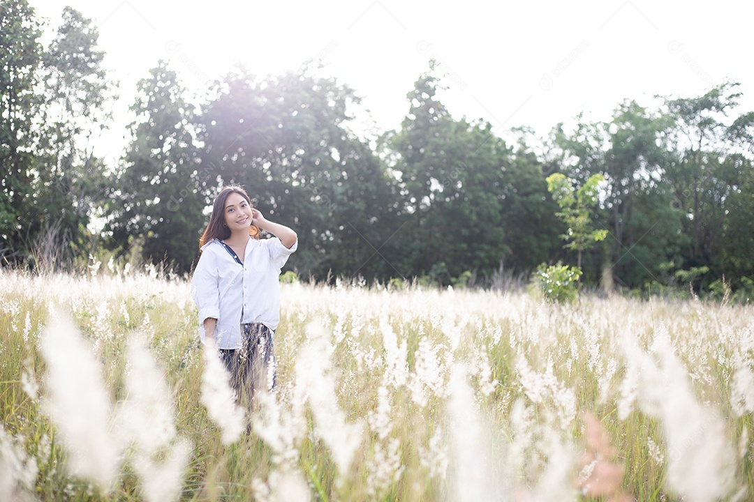 As mulheres asiáticas sorriem felizes no tempo de relaxamento no prado e na grama