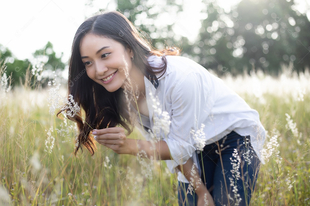 As mulheres asiáticas sorriem felizes no tempo de relaxamento no prado e na grama
