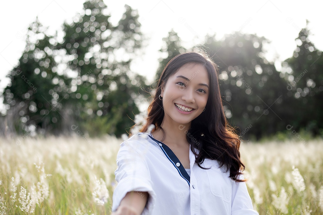 As mulheres asiáticas sorriem felizes no tempo de relaxamento no prado e na grama