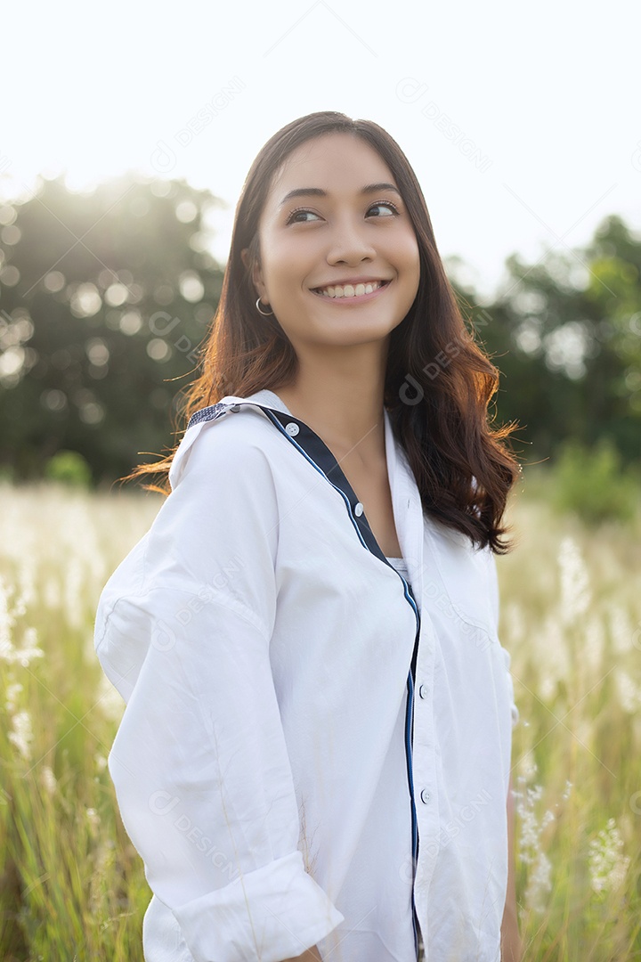 As mulheres asiáticas sorriem felizes no tempo de relaxamento no prado