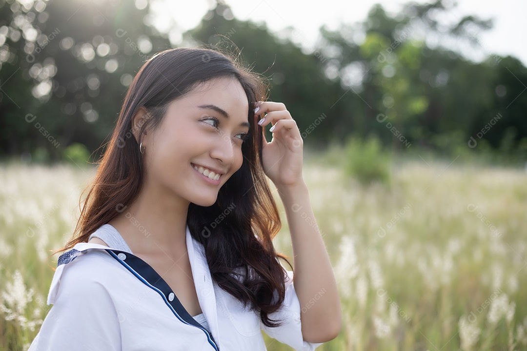 As mulheres asiáticas sorriem felizes no tempo de relaxamento no prado