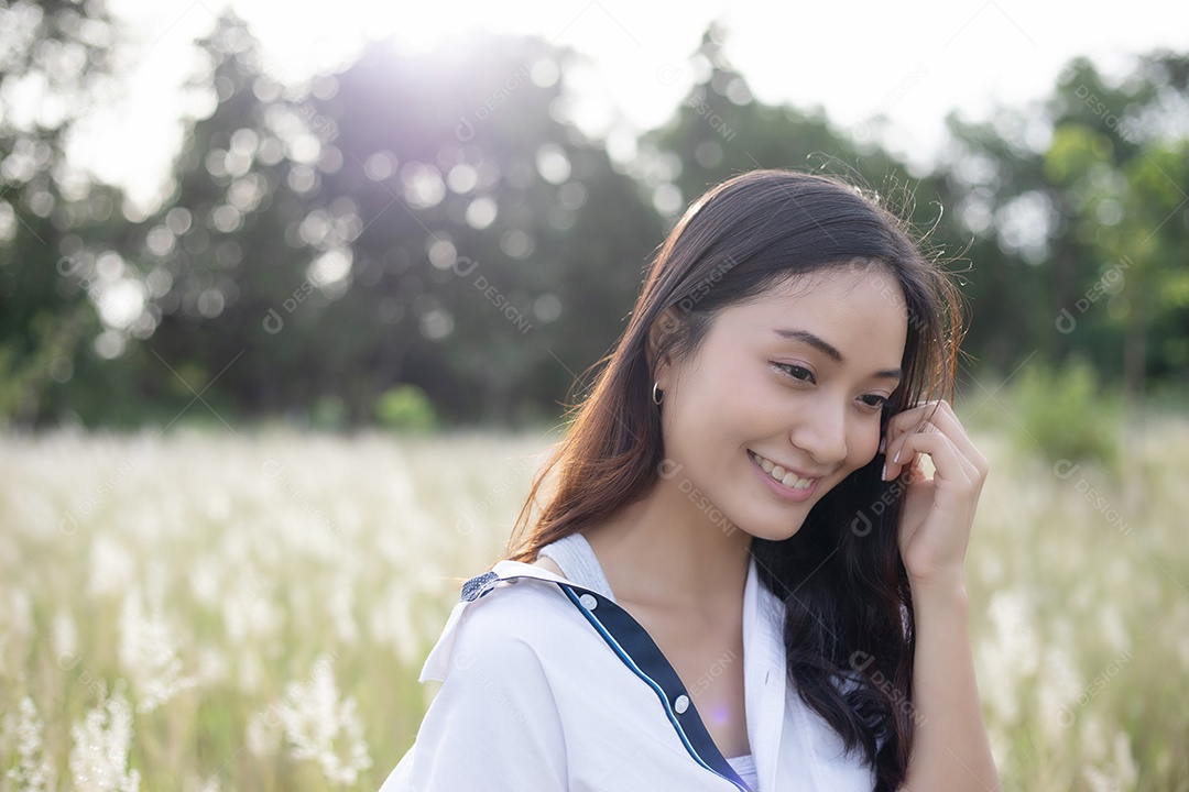 As mulheres asiáticas sorriem felizes no tempo de relaxamento no prado