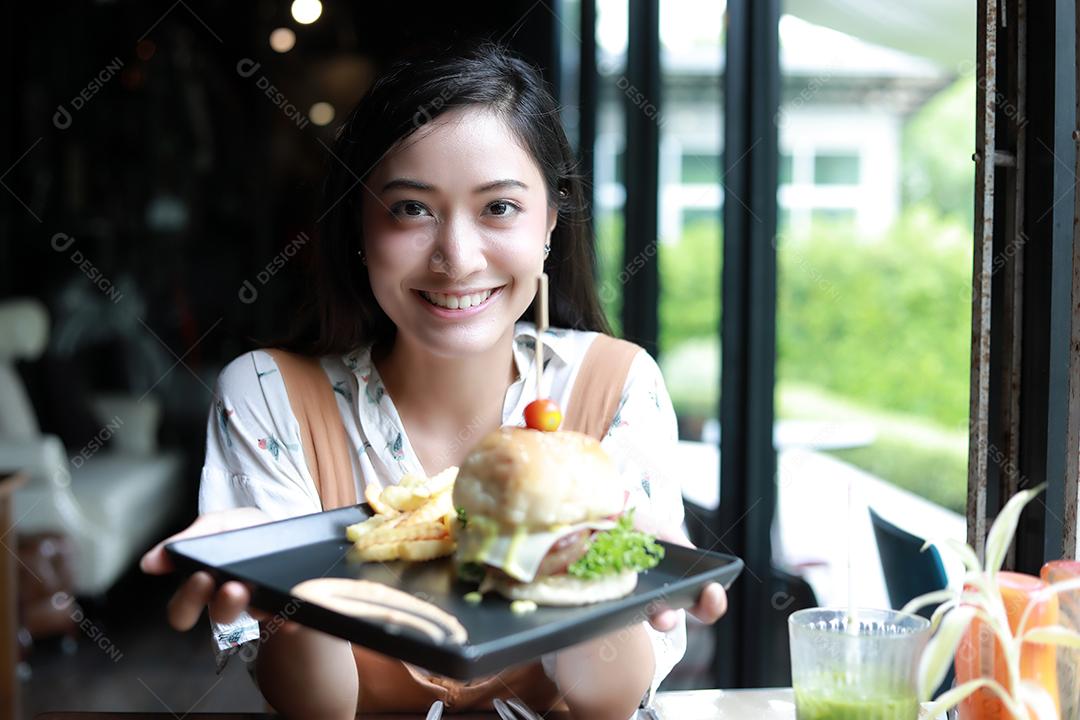 Asian women smiling and happy and enjoying eating hamburgers in cafe and restaurant at relax time