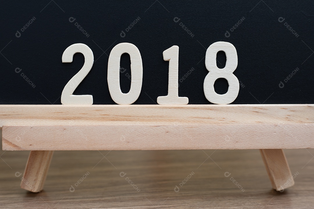 A palavra de madeira dos números de 2018 está na mesa de madeira e no fundo preto