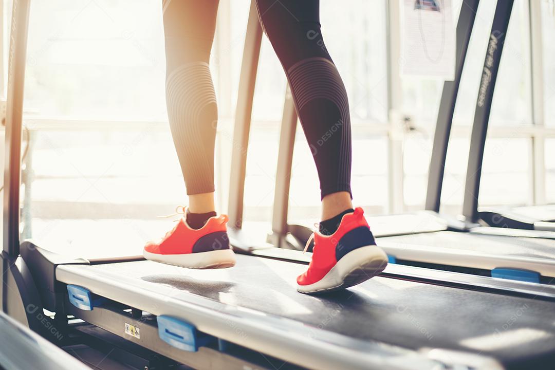 Desfoque de tênis de corrida na academia enquanto uma jovem caucasiana está correndo na esteira