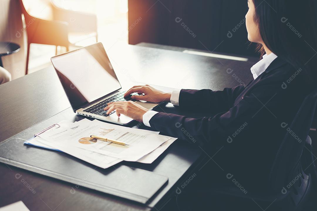 Empresárias asiáticas usando documentos de análise de laptop e diagrama financeiro gráfico na mesa de escritório trabalhando