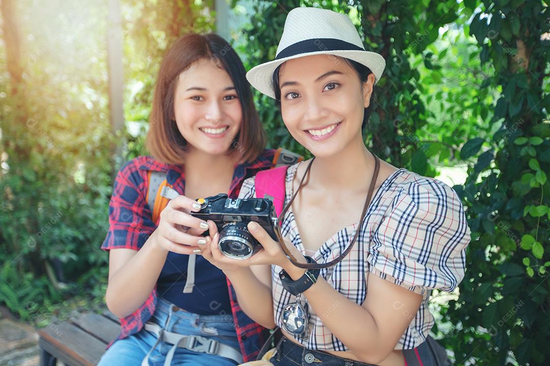 Mochilas de mulheres asiáticas caminhando juntas e felizes estão tirando fotos e olhando fotos, relaxe o tempo em viagens de férias