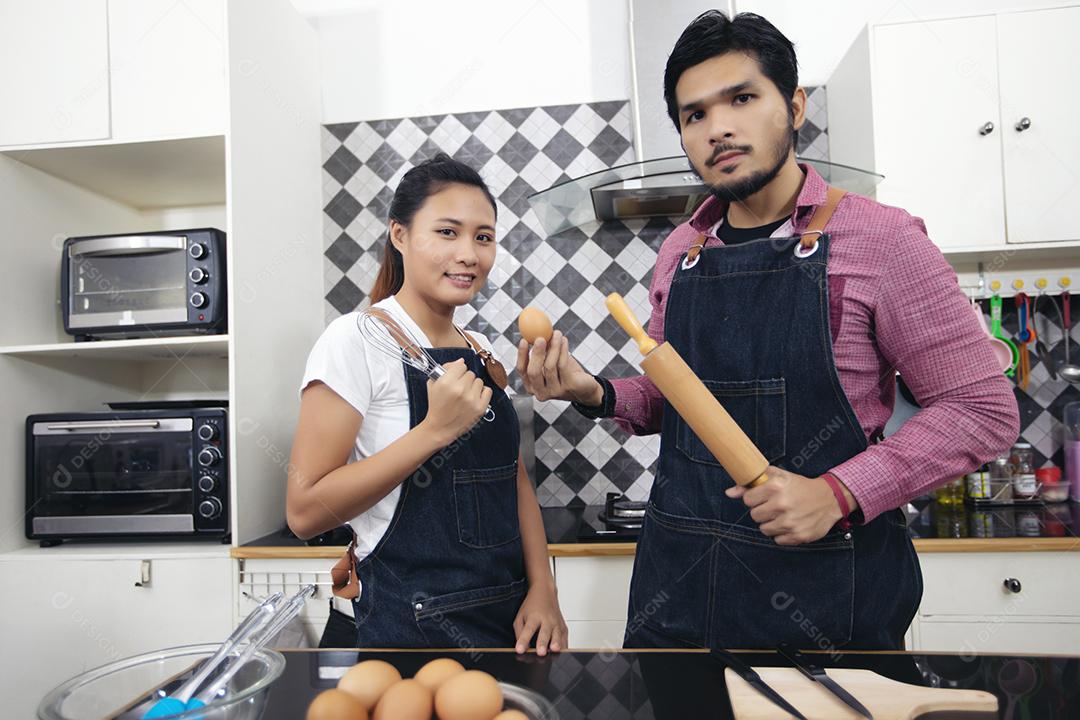 Feliz e sorridente jovem casal cozinhando comida na cozinha em casa