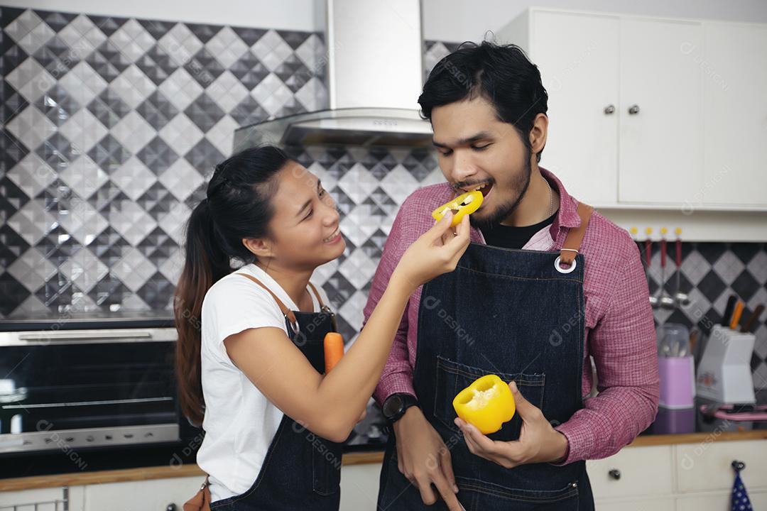 Feliz e sorridente jovem casal cozinhando comida na cozinha em casa