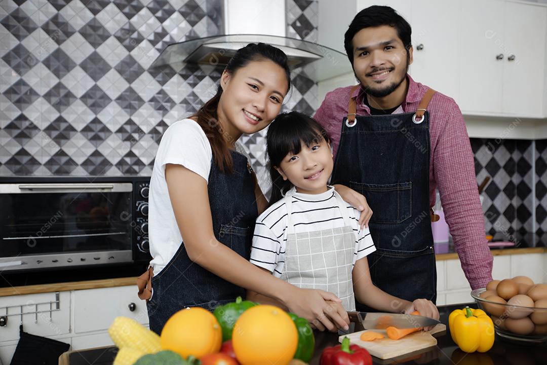 Família feliz tem papai, mamãe e sua filhinha cozinhando juntos na cozinha