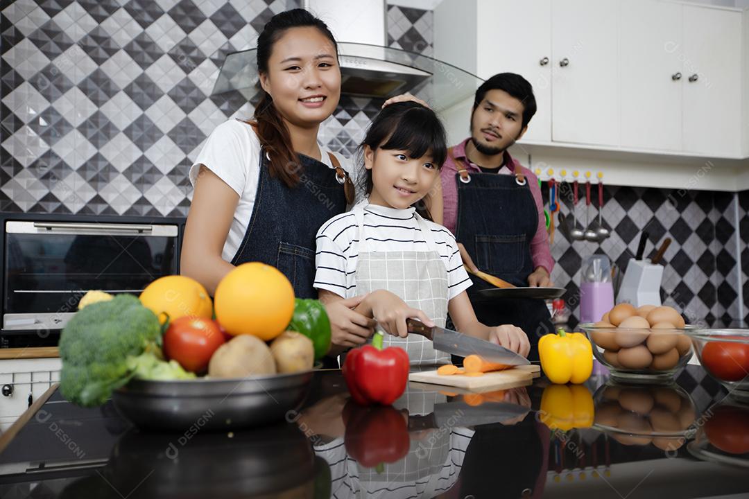 Família feliz tem papai, mamãe e sua filhinha cozinhando juntos na cozinha